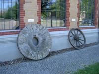Mühlenstein und ein Wagenrad am Bahnhof Altlandsberg